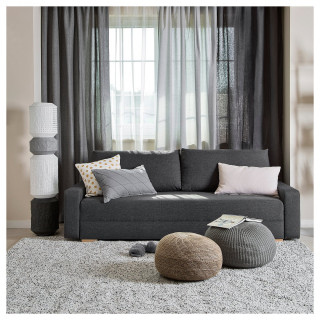 Nowoczesna szara rozkładana sofa z kolorowymi poduszkami, okrągłymi pufami i wysoką białą lampą.