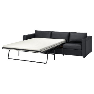 Ciemnoszara rozkładana sofa z czarną metalową ramą i grubym materacem, idealna do małych przestrzeni.