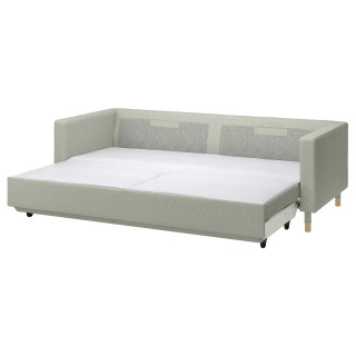 Nowoczesna, jasnozielona rozkładana sofa z drewnianymi nogami i pluszowymi poduszkami.
